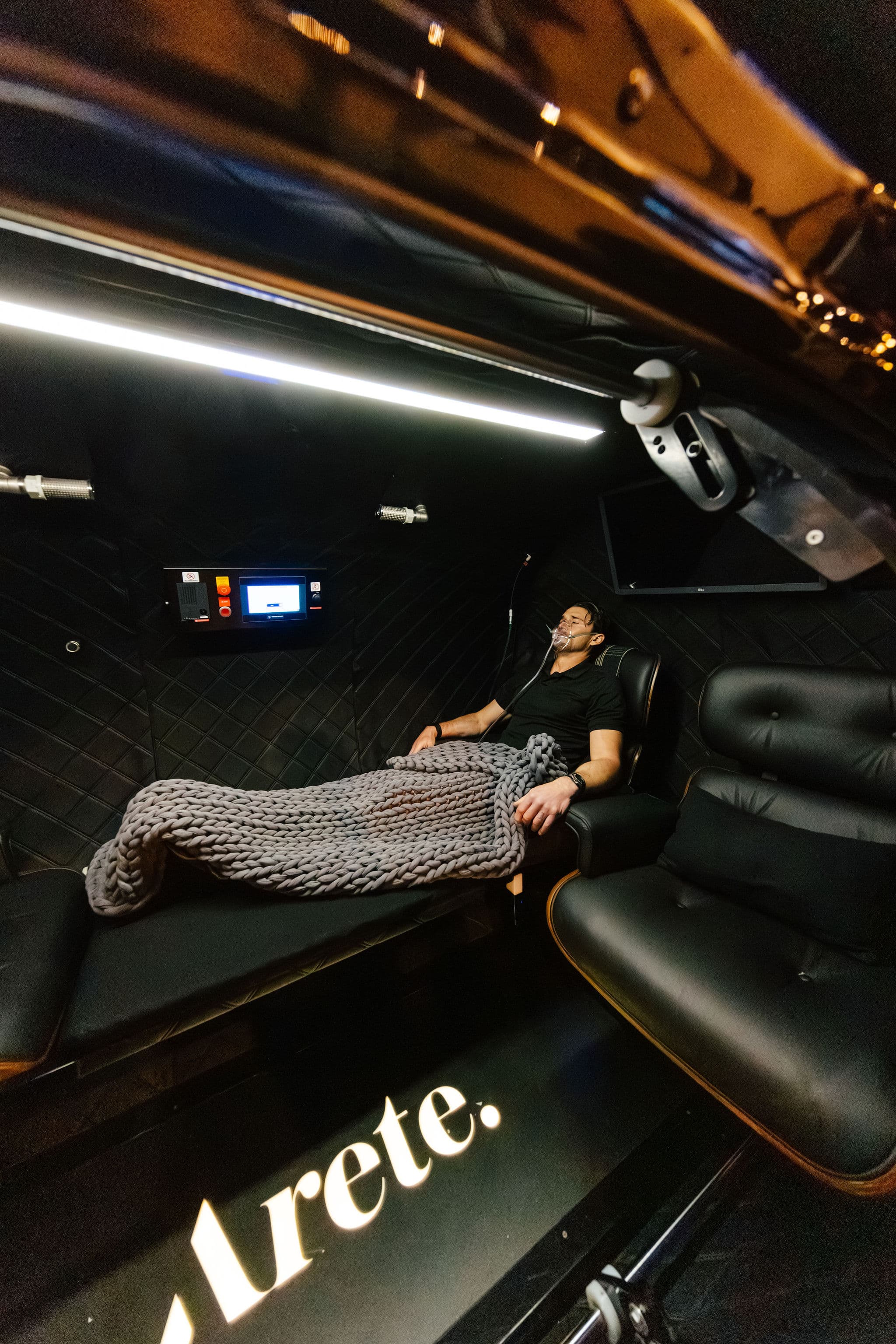 Client resting under a blanket in a recovery chair at Arete